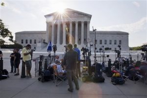 Periodistas hacen guardia frente a la Corte Suprema antes de que se diera a conocer el fallo sobre una controversia a la ley de seguros de salud. Foto: AP