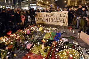 Un grupo de personas sostene una pancarta en la que piede leerse "Yo soy Bruselas", detrás de flores y velas que recuerdan a las víctimas de las explosiones de la capital belga, en la Plaza de la Bolsa, en el centro de Bruselas, el 22 de marzo de 2016. (Foto AP/Martin Meissner)